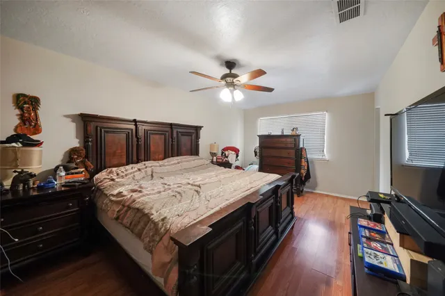 a bed sitting in a bedroom and a flat tv screen on dresser