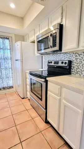 a kitchen with granite countertop a stove a microwave a refrigerator a sink and cabinets