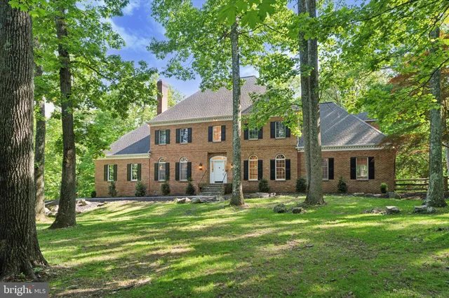a front view of a house with a garden and trees