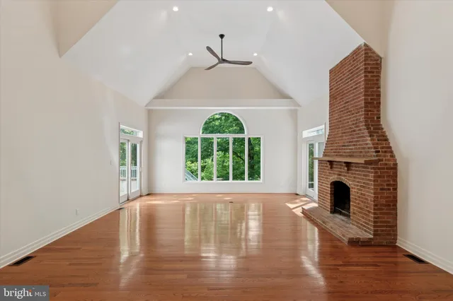 a view of an empty room with wooden floor fireplace and a window