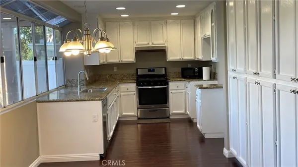 a kitchen with stainless steel appliances granite countertop a refrigerator a stove a sink and a microwave