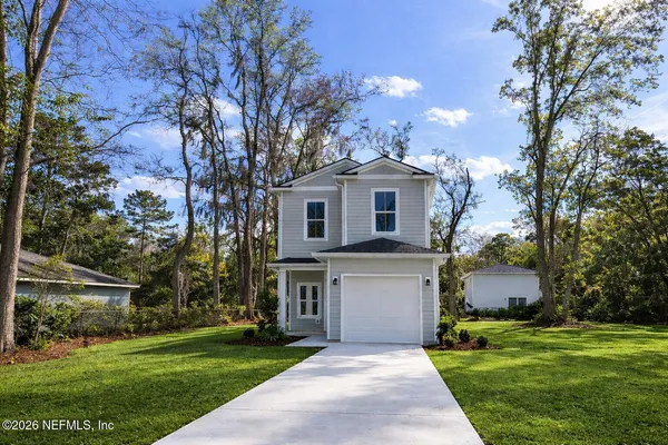 a front view of a house with a garden and trees