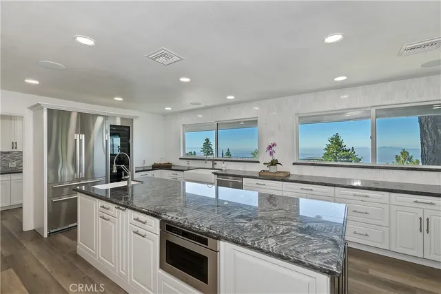 a kitchen with stainless steel appliances granite countertop a lot of cabinets and wooden floor