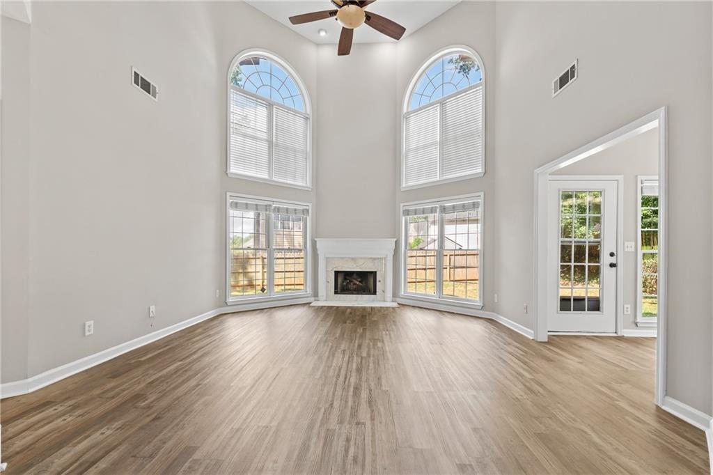 2878 Calhoun Square Suwanee, GA 30024 - Photo 11 of 42 an empty room with wooden floor fireplace and windows