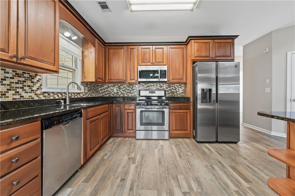 2878 Calhoun Square Suwanee, GA 30024 - Photo 17 of 42 a kitchen with stainless steel appliances a refrigerator a sink a stove and cabinets