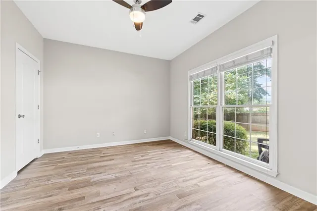 an empty room with wooden floor fireplace and windows