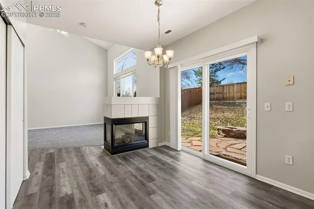 a room with fireplace chandelier and wooden floor