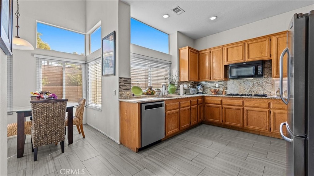 1671 Dominguez Ranch Road Corona, CA 92878 - Photo 15 of 42 a kitchen with stainless steel appliances granite countertop wooden cabinets a stove a sink and a refrigerator