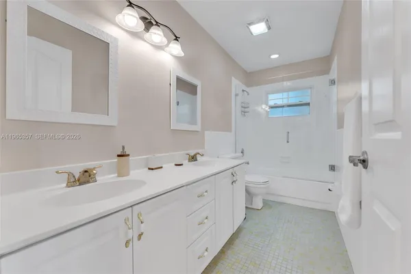a bathroom with a double vanity sink toilet mirror and bathtub