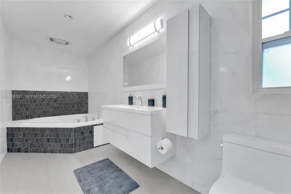 a bathroom with a tub a sink and a mirror