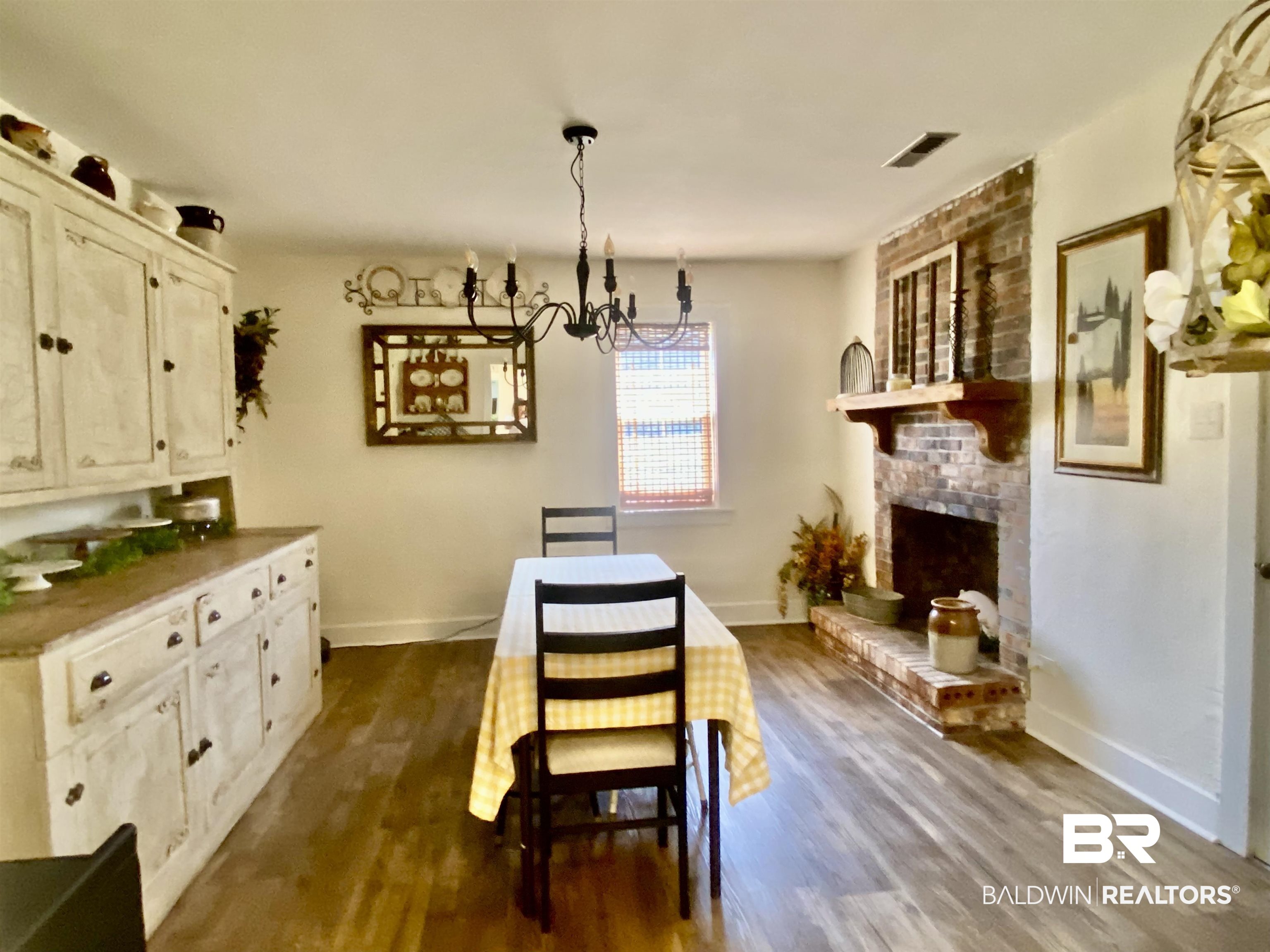 531 Highway 136 Monroeville, AL 36460 - Photo 20 of 48 Dining space featuring brick wall, an inviting chandelier, a brick fireplace, and dark wood-type flooring