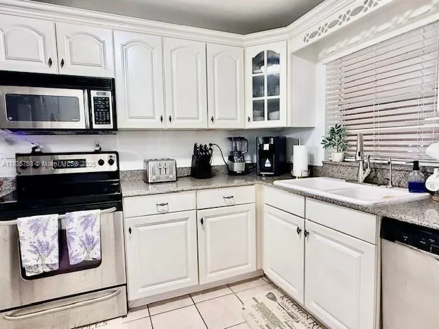 a kitchen with granite countertop white cabinets and black stainless steel appliances