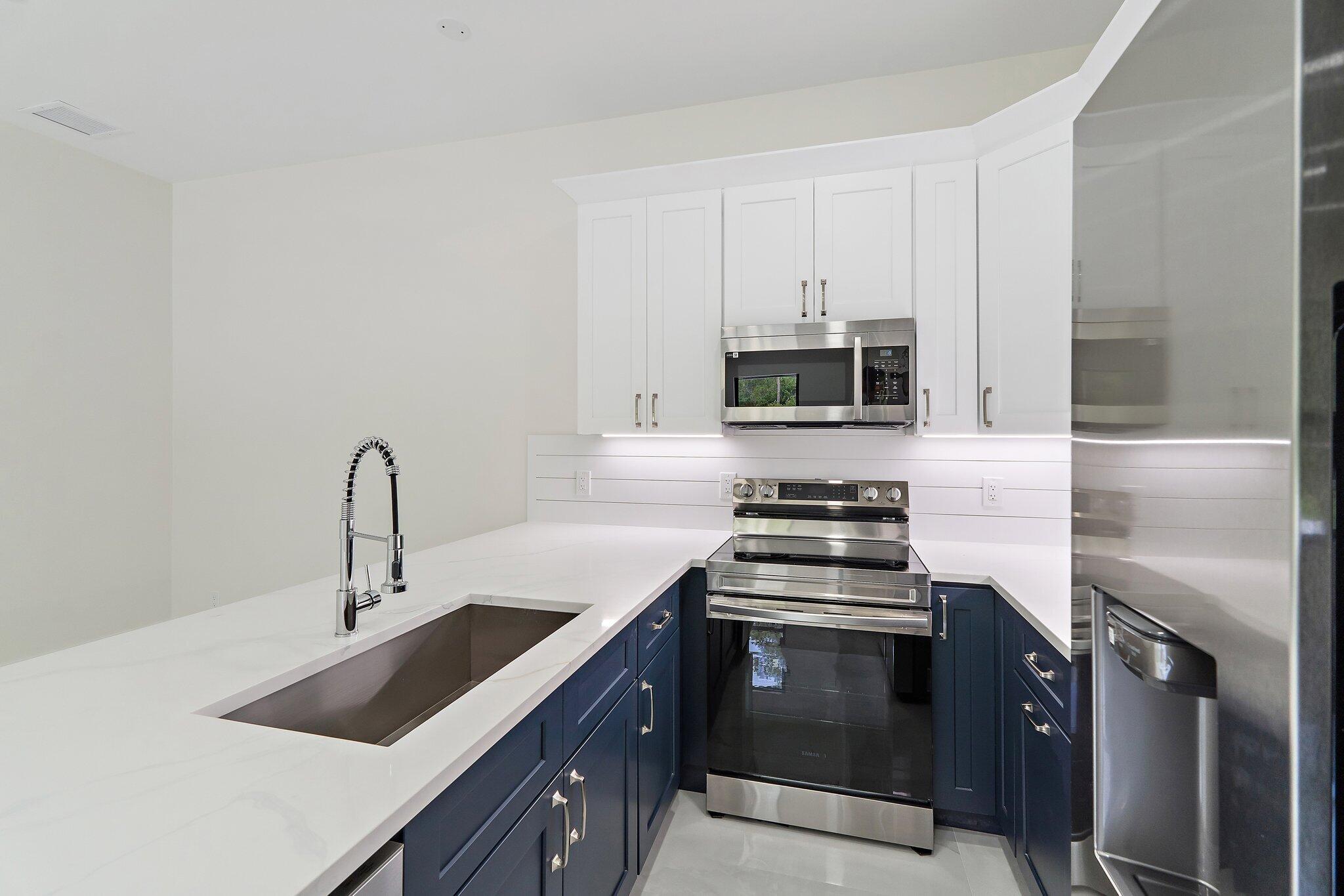 12850 152nd Street North Jupiter, FL 33478 - Photo 96 of 117 a kitchen with stainless steel appliances a stove microwave and sink