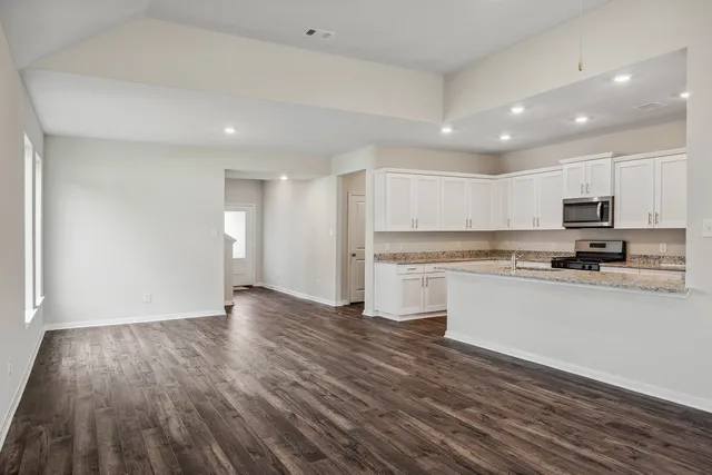 a view of a kitchen with wooden floor and electronic appliances
