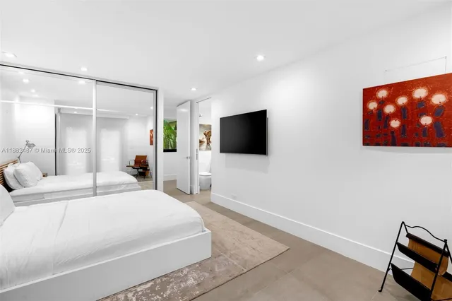 a bedroom with a bed a tv and wooden floor