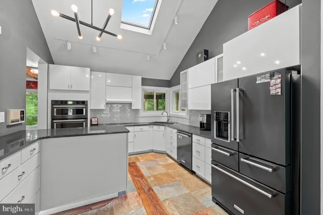 a kitchen with stainless steel appliances granite countertop a refrigerator a stove a sink dishwasher a oven with white cabinets and wooden floor