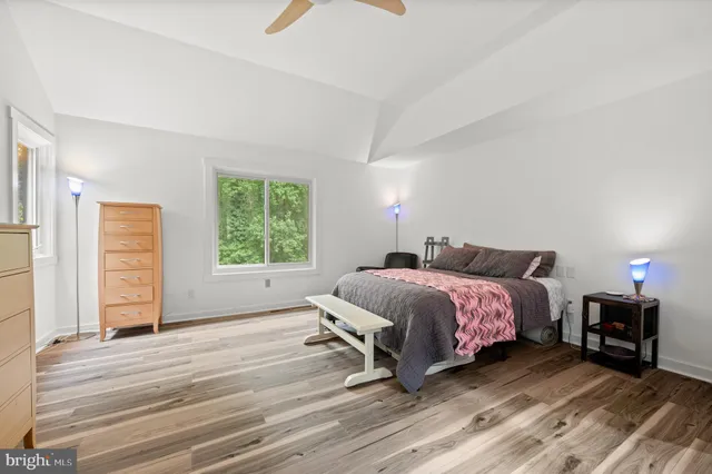 a spacious bedroom with a bed a window and dresser