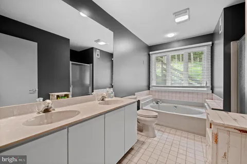 a bathroom with a granite countertop sink a toilet a large mirror and bathtub