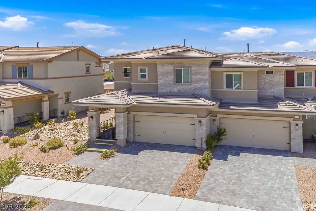 913 Cadence View Way Henderson, NV 89011 - Photo 3 of 46 A striking modern facade features a combination of stone and stucco, with ample garage space and a neatly paved driveway.