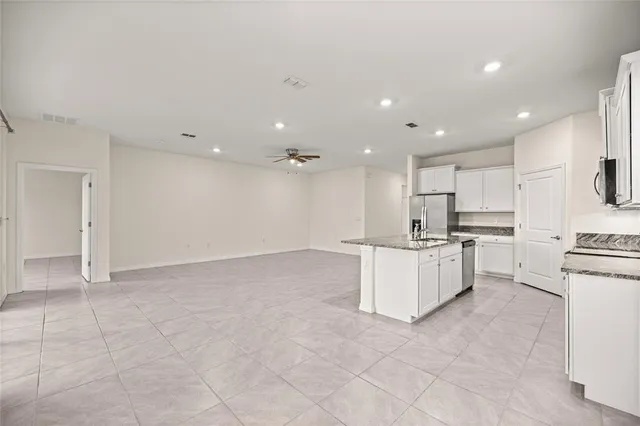 a large white kitchen with kitchen island a sink a stove a refrigerator and white cabinets