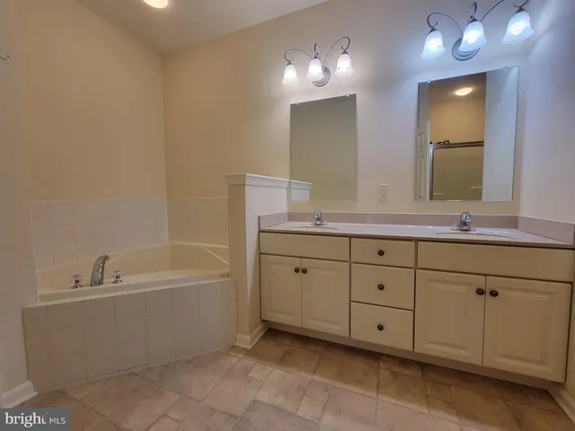 a spacious bathroom with double sink a large mirror and a bathtub