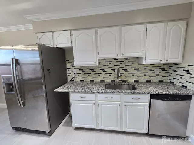 a kitchen with granite countertop a sink and a refrigerator