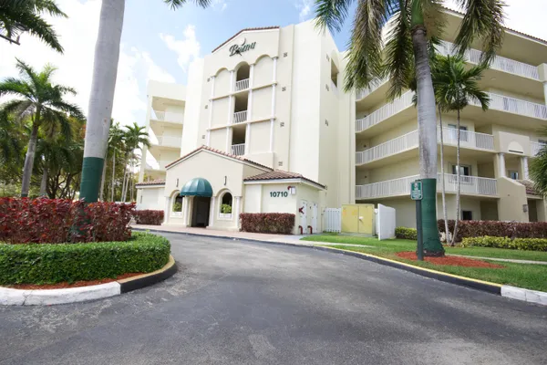 a view of a white building among the street with palm trees