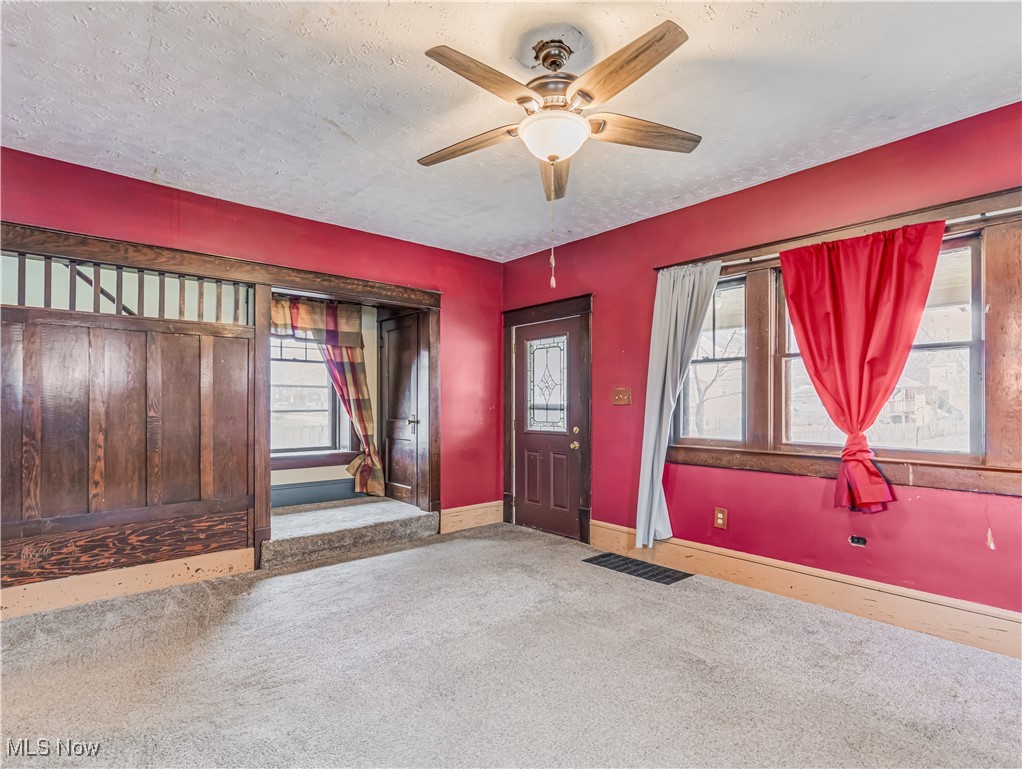 1095 Chalker Street Akron, OH 44310 - Photo 6 of 19 Carpeted foyer entrance with visible vents, baseboards, a textured ceiling, and a ceiling fan