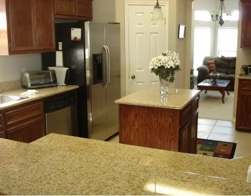 a kitchen with stainless steel appliances kitchen island granite countertop a refrigerator and a sink