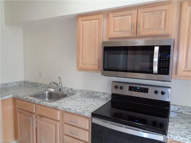 a kitchen with granite countertop a stove microwave and sink