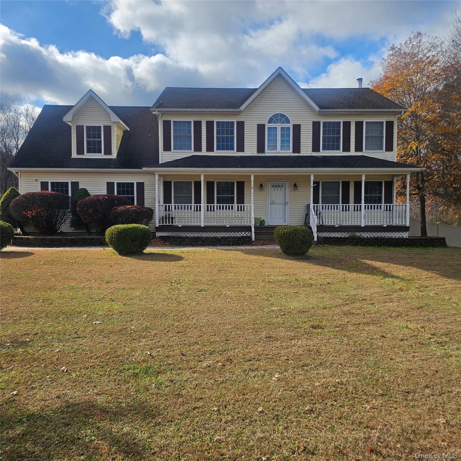 Colonial home featuring covered porch and a front yard