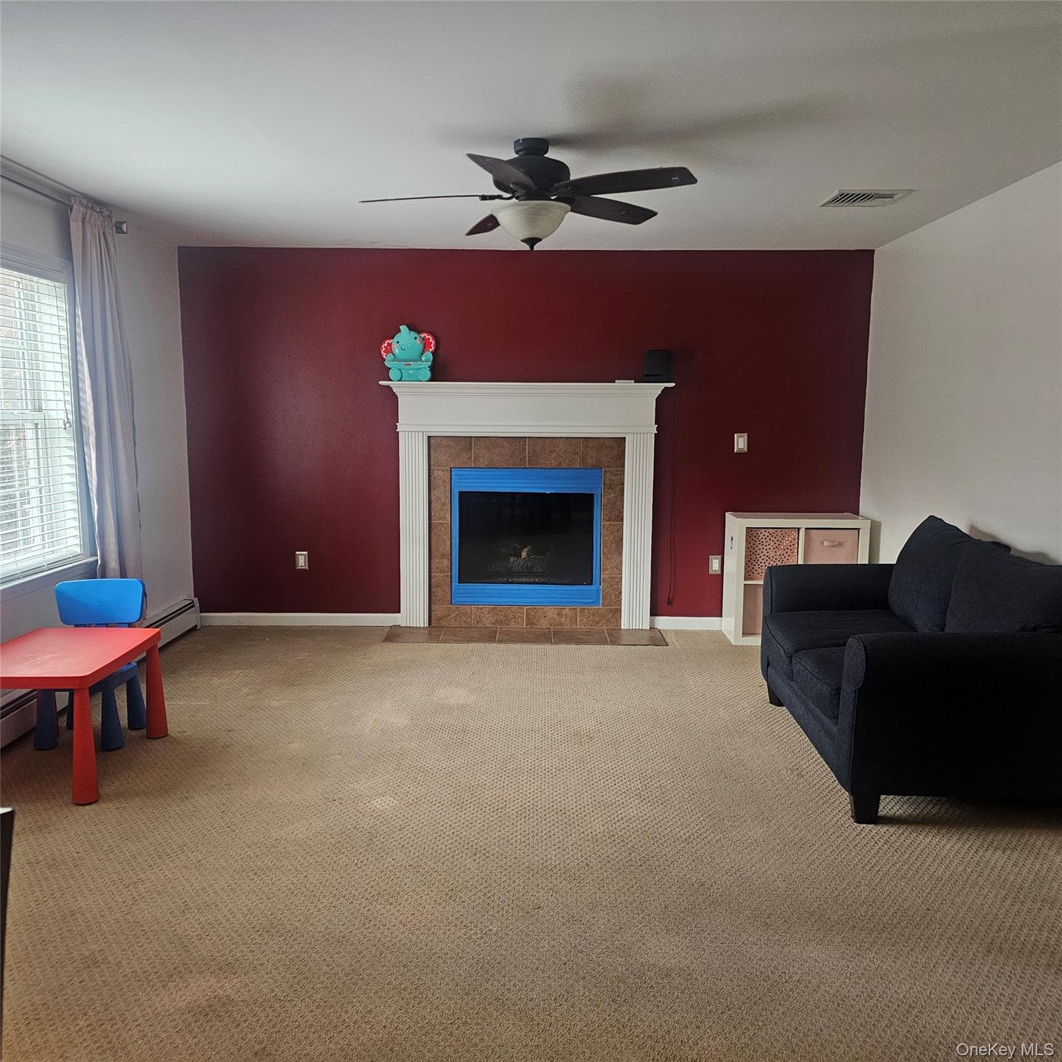 235 Maples Road Middletown, NY 10940 - Photo 9 of 34 Living area with carpet floors, a fireplace, ceiling fan, and a baseboard heating unit