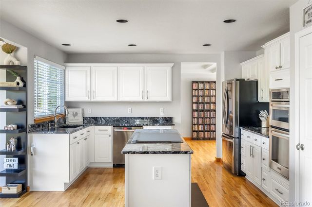 a kitchen with stainless steel appliances a stove a refrigerator a sink and white cabinets