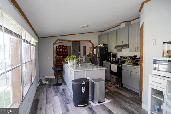 a kitchen with kitchen island a counter top space a sink stainless steel appliances and cabinets