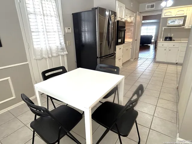 a kitchen with stainless steel appliances kitchen island granite countertop a refrigerator a stove a sink a dining table and chairs