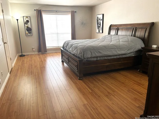 a spacious bedroom with a bed and wooden floor