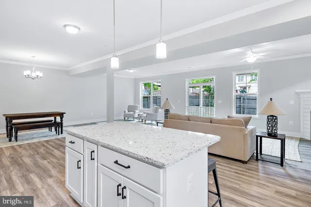 a dining hall with stainless steel appliances granite countertop a sink dishwasher and a dining table with wooden floor