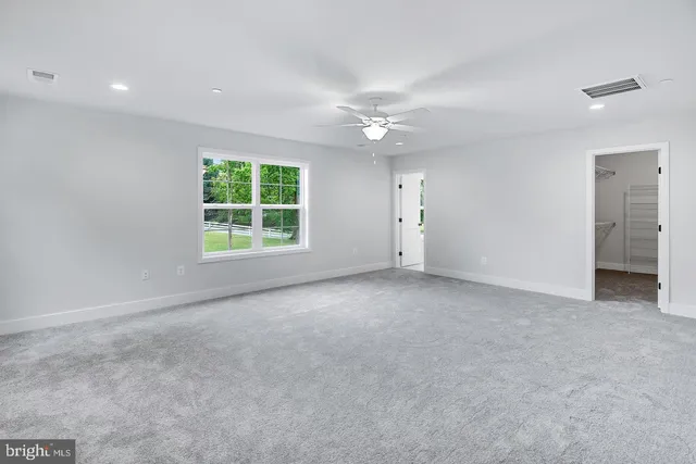 an empty room with windows closet and chandelier fan