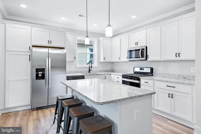 a kitchen with kitchen island granite countertop a sink a counter space stainless steel appliances and cabinets