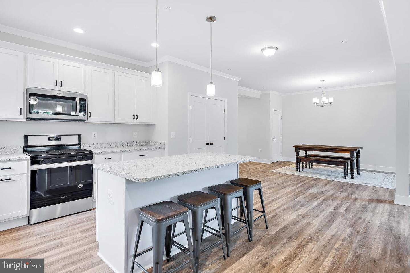 404 Paradise Road Riva, MD 21140 - Photo 9 of 51 a kitchen with stainless steel appliances granite countertop a stove a sink a microwave a refrigerator and white cabinets with wooden floor