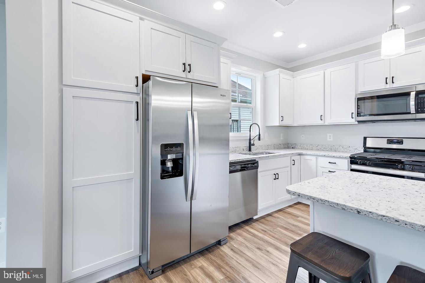 404 Paradise Road Riva, MD 21140 - Photo 10 of 51 a kitchen with a refrigerator stainless steel appliances wooden floor and cabinets