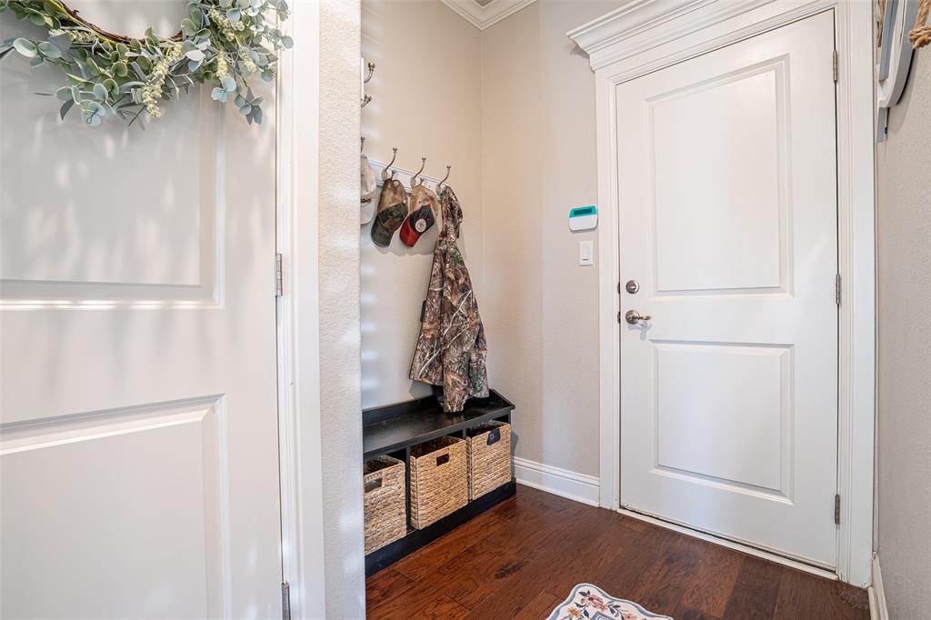 1920 Meander Road Granbury, TX 76049 - Photo 23 of 40 Entryway featuring a white paneled door with decorative trim, wood-finish flooring, and a built-in bench with storage cubbies