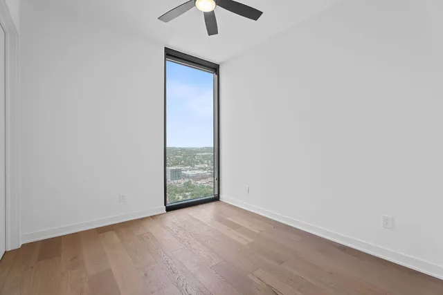 an empty room with a ceiling fan and wooden floor