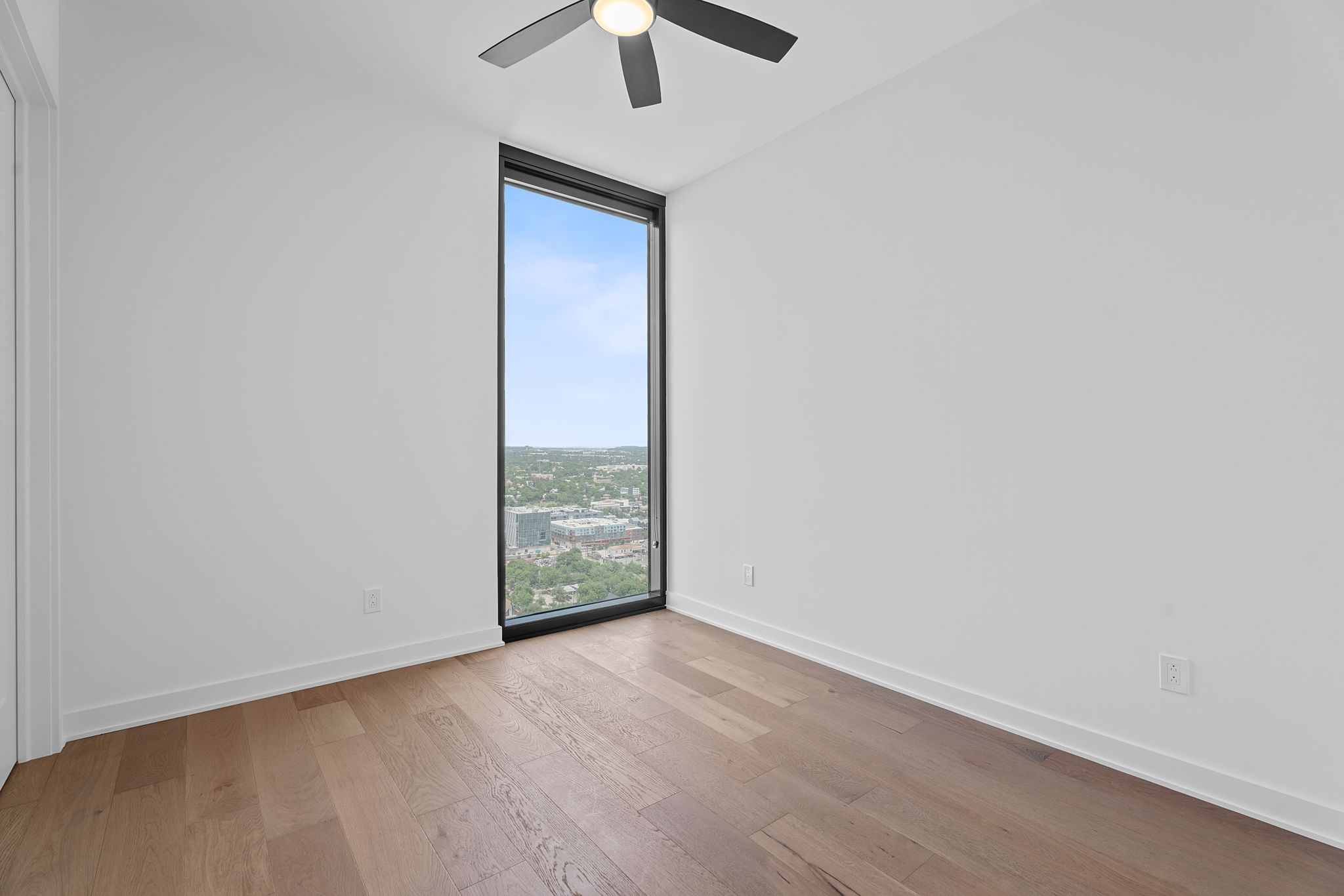 84 East Avenue, Unit 3401 Austin, TX 78701 - Photo 21 of 40 an empty room with a ceiling fan and wooden floor