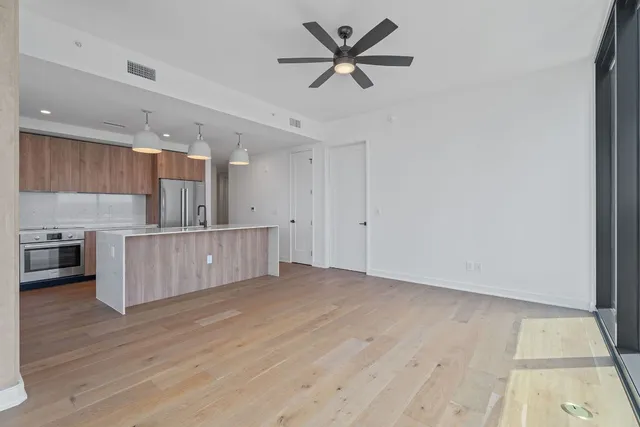 a view of kitchen and empty room with wooden floor
