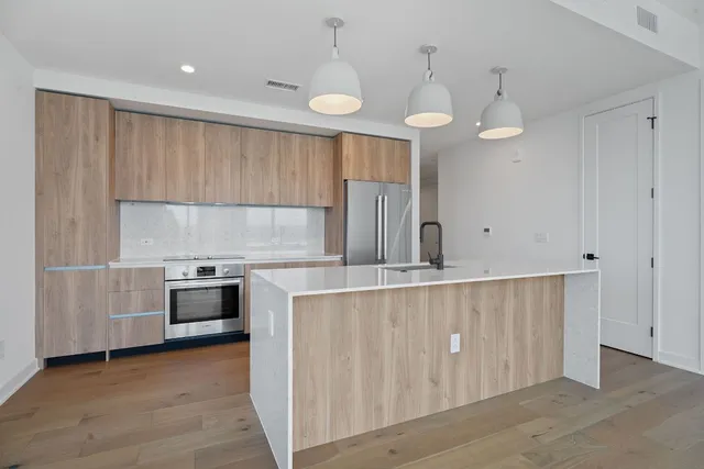 a kitchen with stainless steel appliances a stove a sink a center island and cabinets