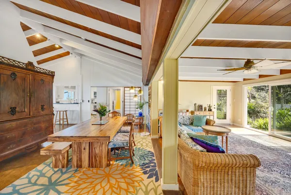 a living room with furniture large windows and kitchen view