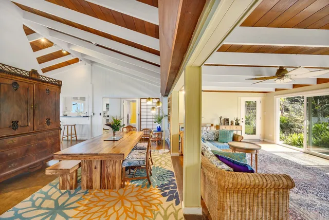 a living room with furniture large windows and kitchen view
