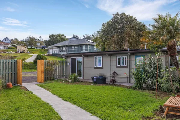 a living room with stainless steel appliances kitchen island granite countertop a refrigerator a table and chairs with wooden floor