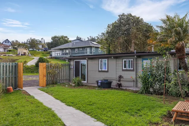 a living room with stainless steel appliances kitchen island granite countertop a refrigerator a table and chairs with wooden floor